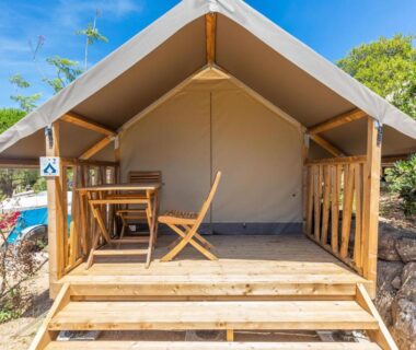 Terrasse en bois avec table et chaises devant une tente safari au Camping Rondinara