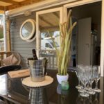 Terrasse couverte avec seau à champagne et verres sur table au Camping SIBLU Les Viviers 4 étoiles