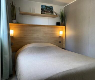 Chambre avec lit double et éclairage mural au Camping SIBLU Les Viviers