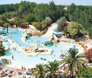 Piscine lagon avec toboggans et palmiers au Camping Sable d'Or 3 chambres