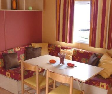 Coin repas avec banquette et table dans le mobil-home Camping Sable d'Or 3 chambres