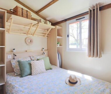 Intérieur chambre avec lit double, coussins et fenêtre au Camping Saint Laurent