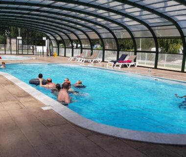 Piscine couverte avec baigneurs et transats au Camping Saint Laurent