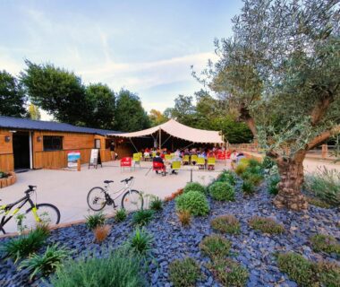 Espace extérieur avec terrasse couverte, tables et vélos au Camping Saint Laurent