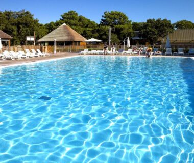 Piscine extérieure avec transats et bungalows au Camping San Damiano