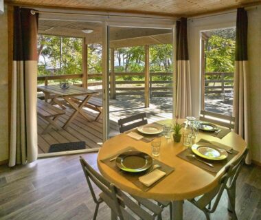 Intérieur avec table à manger et terrasse en bois du Camping San Damiano