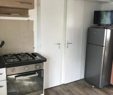 Coin cuisine avec four plaques et réfrigérateur dans le mobil home du Camping Siblu