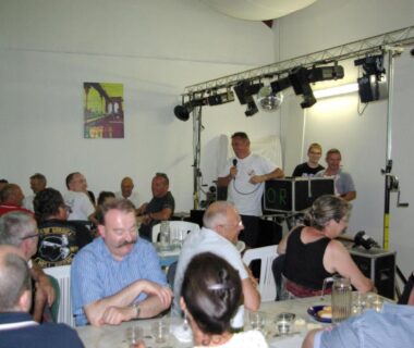 Salle commune avec tables convives et scène au Camping Smile et Braudieres