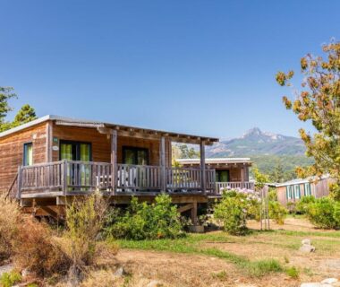 Terrasses sur pilotis avec chalets et montagne en arrière-plan au Camping Sole Di Sari