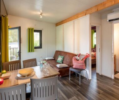 Intérieur avec coin repas et salon dans le mobil-home du Camping Sole Di Sari