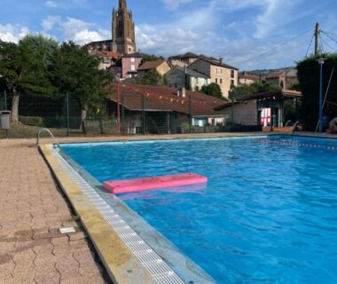 Piscine extérieure et clocher de village en arrière plan au Camping Sud AVEYRON dans le Rougier