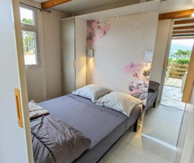 Chambre avec lit double et poutres apparentes au Camping TIKITI