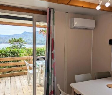 Terrasse en bois avec table et vue mer depuis le mobil-home du Camping TIKITI