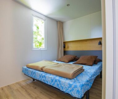 Chambre avec lit double et fenêtre dans le mobil-home du Camping Taxo Les Pins Maeva