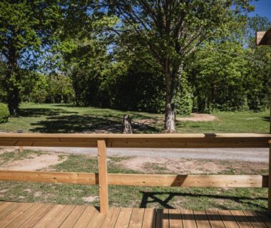 Terrasse en bois donnant sur pelouse et arbres au Camping Terre d'Armor