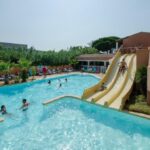 Piscine extérieure avec toboggans et transats au Camping Tikayan Clau Mar Jo Maeva
