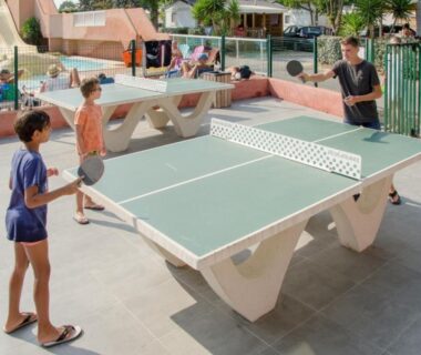 Espace extérieur près de la piscine avec table de ping-pong et joueurs au Camping Tikayan Clau Mar Jo Maeva