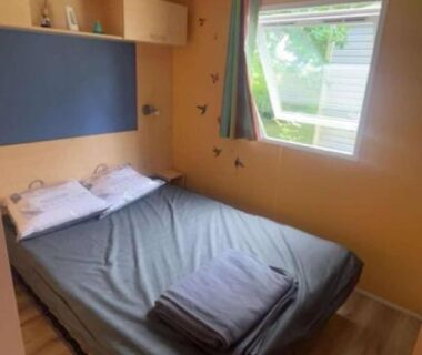 Chambre avec lit double et fenêtre dans l'hébergement du Camping Tohapi Coeur de Vendée