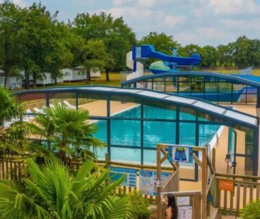 Espace piscine couvert avec toboggans et palmiers au Camping Tohapi Coeur de Vendée