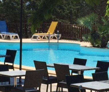 Bord de piscine avec chaises longues et terrasse au Camping Trinité