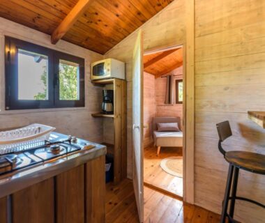 Intérieur de mobil-home avec kitchenette et chambre visible au Camping U Pirellu