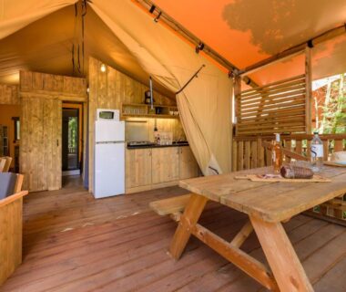 Intérieur de tente avec cuisine et table en bois au Camping U Pirellu