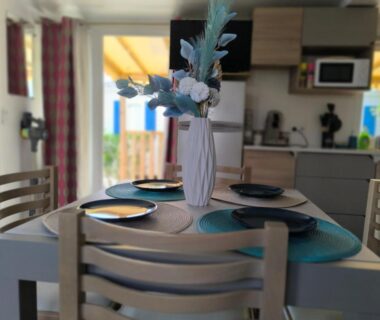 Coin repas avec table dressée et vase dans le locatif du Camping Valras Les Sables du Midi