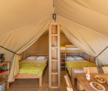 Intérieur de tente avec deux lits et coin repas au Camping Vigna Maggiore
