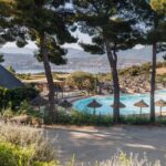 Bord de piscine avec parasols et vue sur la mer au Camping Vigna Maggiore