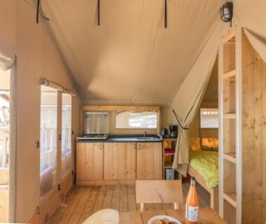 Intérieur de tente lodge avec kitchenette et lits au Camping Vigna Maggiore