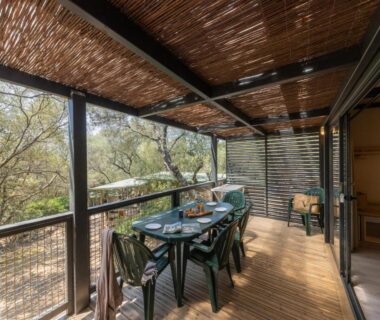 Terrasse couverte avec table et chaises dans la végétation au Camping Vigna Maggiore