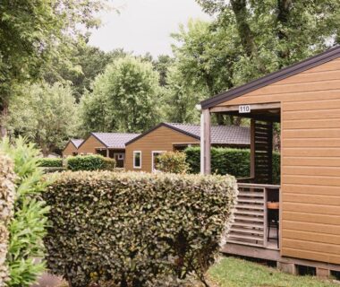 Allée bordée de haies et mobil-homes en bois dans le Camping ZELAIA