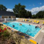Piscine extérieure avec baigneurs et transats au Camping de Brouël