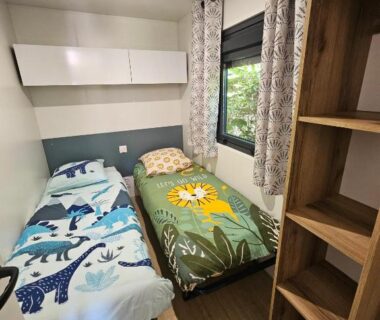 Chambre avec deux lits et étagère dans l'hébergement du Camping de Charlieu