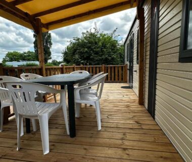 Terrasse en bois couverte avec table et chaises du Camping de Charlieu
