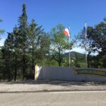 Entrée du camping avec drapeaux et mur signalétique au Camping de Graniers