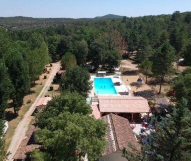 Piscine du camping entourée de pins au Camping de Graniers