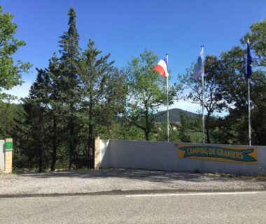 Entrée du camping avec drapeaux et mur signalétique au Camping de Graniers