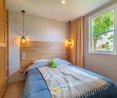 Chambre avec lit double lampe suspendue et fenêtre au Camping de La Hallerais Dinan