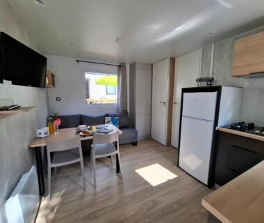 Intérieur avec coin salon et kitchenette dans le mobil-home du Camping de La Piscine