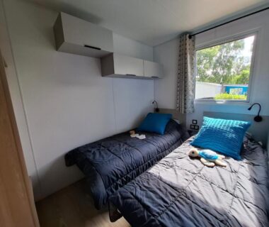 Chambre avec deux lits simples et fenêtre donnant sur l'extérieur du camping au Camping de La Piscine
