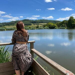 Terrasse en bois au bord du lac avec une personne contemplant au Camping de Matour – ONLYCAMP
