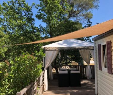 Terrasse en bois avec tonnelle et salon extérieur au Camping de Parpaillon