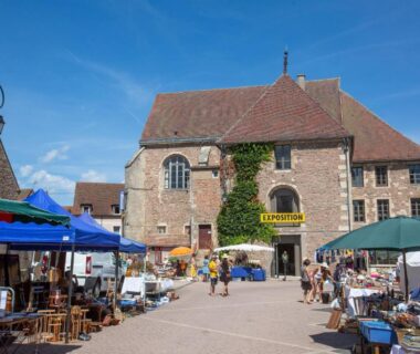 Place du marché avec étals et parasols au Camping de Saulieu