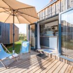 Terrasse en bois avec chaises longues parasol et portes vitrées du Camping de Saverne