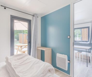 Chambre avec lit et serviettes pliées près de la baie vitrée au Camping de Saverne