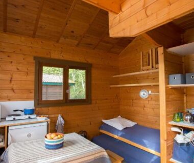 Intérieur du chalet avec table coin repas et lits superposés du Camping de Tauves