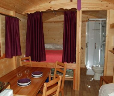 Intérieur en bois avec coin repas kitchenette et lit dans le chalet du Camping de Trezulien