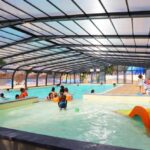 Piscine couverte avec pataugeoire et transats au Camping de l’Etang du Pays Blanc