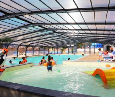 Piscine couverte avec pataugeoire et transats au Camping de l’Etang du Pays Blanc